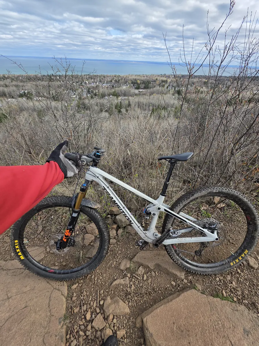 A mud-flecked mountain bike leaned against the rocks on an overlook, with the town and lake far below